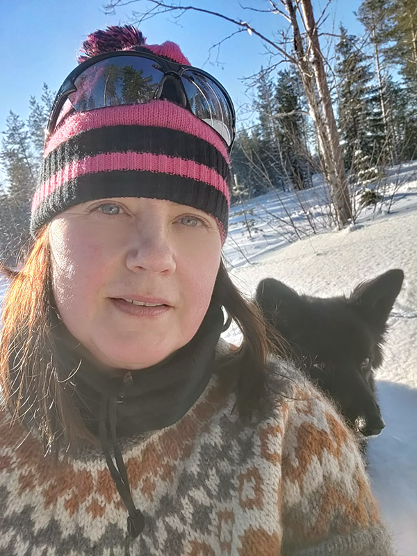 Minna Raninen lumisessa metsässä koiran kanssa.