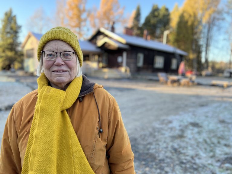Nainen keltaisissa vaatteissa vanhan rakennuksen pihalla.