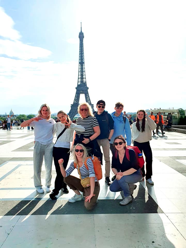 Joukko ihmisiä poseeraa, taustalla Eiffel-torni