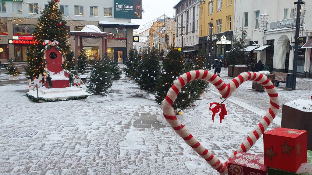 Joulukuusia Oulun Rotuaarilla. Puiden katveessa iso tuoli, ehkä joulupukkia varten. Etualalla sydämen muotoinen koriste.