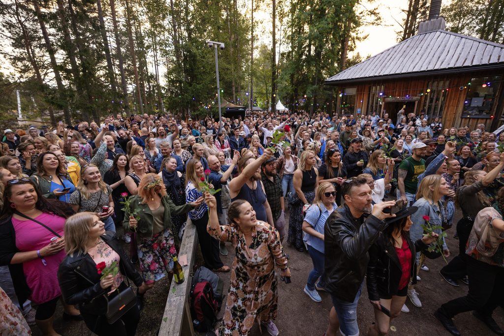 Yleisöjoukko seuraa konserttia luonnon keskellä.