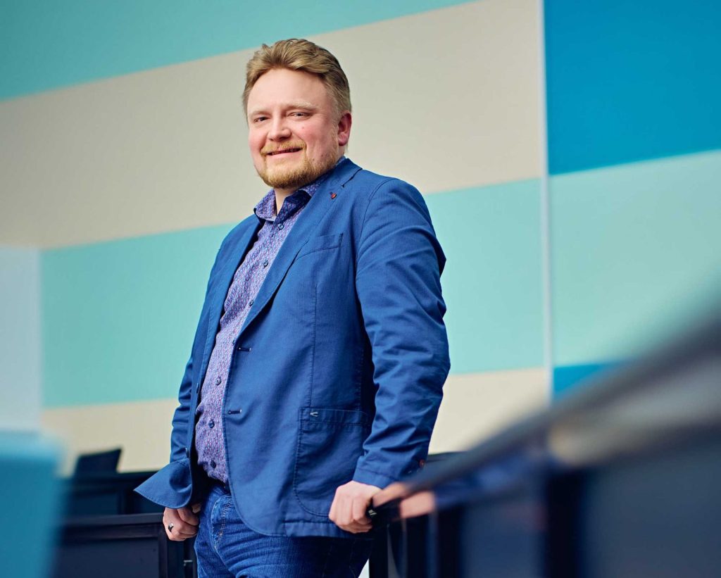 A middle-aged man in a blue blazer in an auditorium.