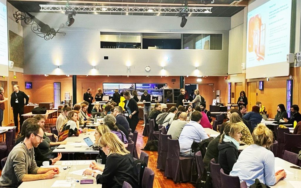 A large group of people discussing in a conference room.