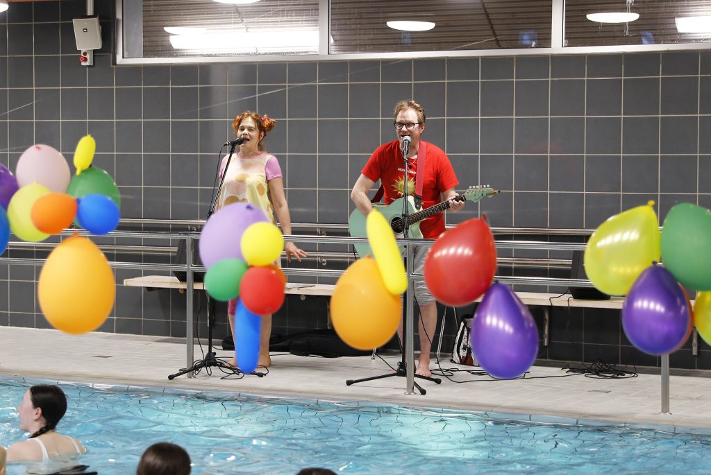 A duo performing by a swimming pool