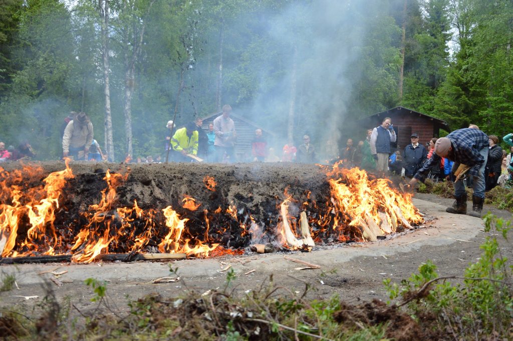 Ihmisiä palavan tervahaudan ympärillä.