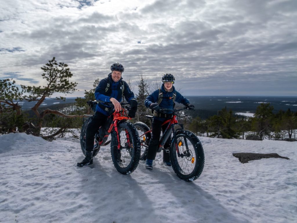 Mies ja poika maastopyörien selässä tunturimaisemassa.
