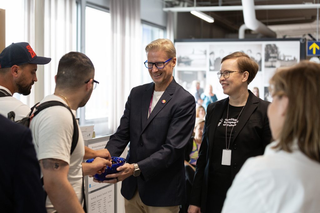 Mies ja nainen tarjoilevat suklaakonvehteja lentoaseman portilla.