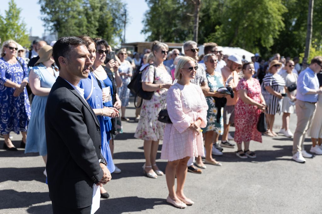Yleisöä kutsuvierastilaisuudessa ulkona.