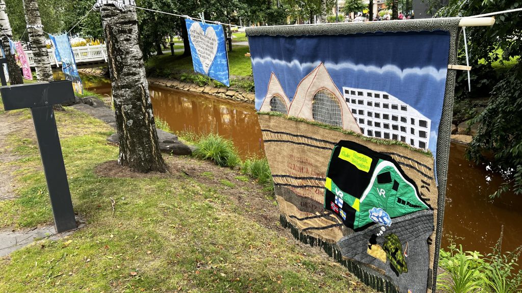 Tilkkutäkkiteos roikkuu narulla puistossa.