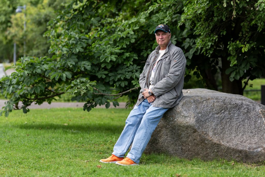 Mies nojaa suureen kiveen puistossa.