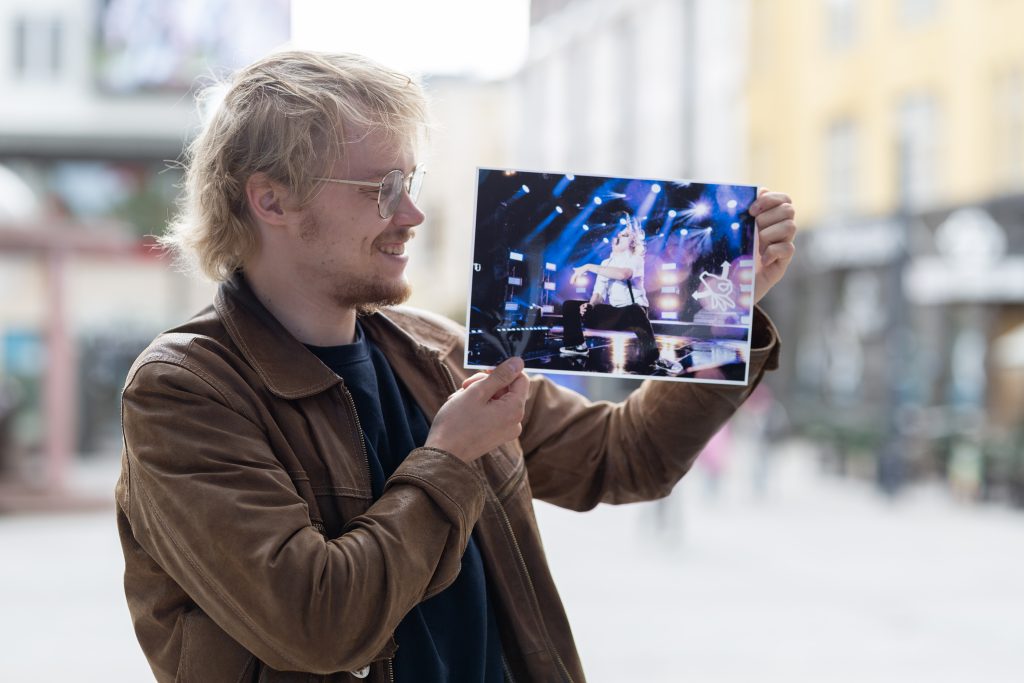 Mies pitelee valokuvaa itsestään soittamassa ilmakitaraa.