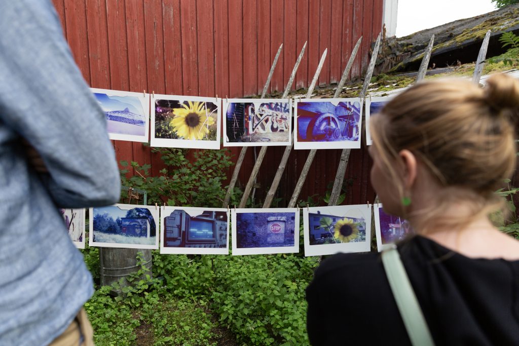 Mies ja nainen katselevat aitaan ripustettuja valokuvia.