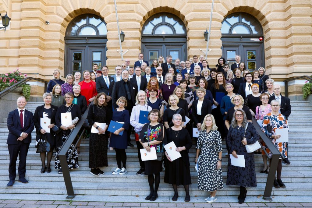 Joukko ihmisiä poseeraa kaupungintalon portailla.