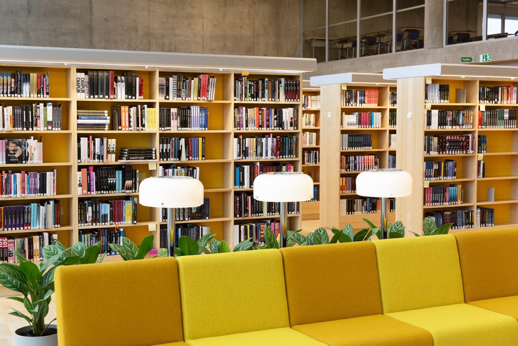 Kirjastosali, etualalla keltasävyinen sohva.