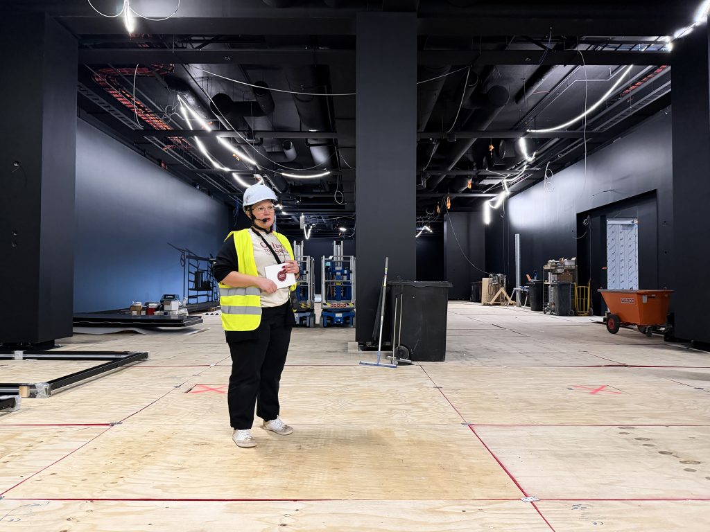 Nainen suuressa salissa työmaavarusteissa.