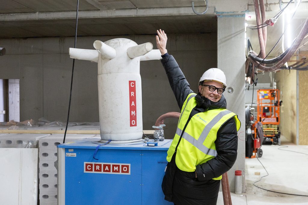 Työmaapukuinen mies kokeilee kädellä puhaltimesta tulevaa ilmaa.