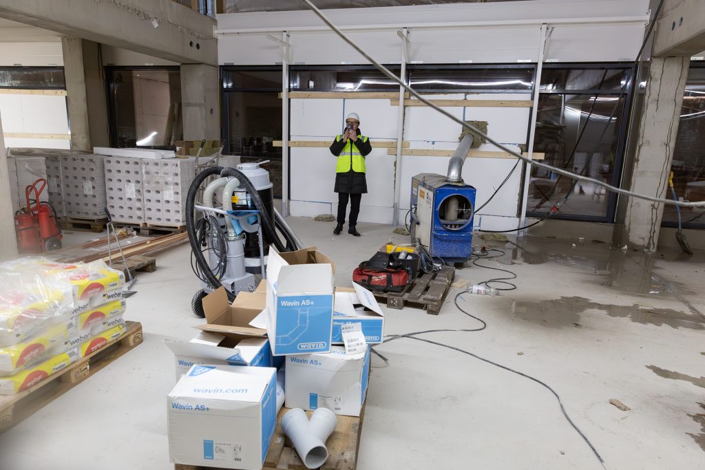 Mies ottaa puhelimella kuvaa rakennustyömaalla.