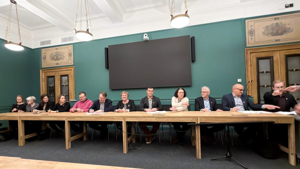 12 kaupunginvaltuutettua pitkän pöydän ääressä.