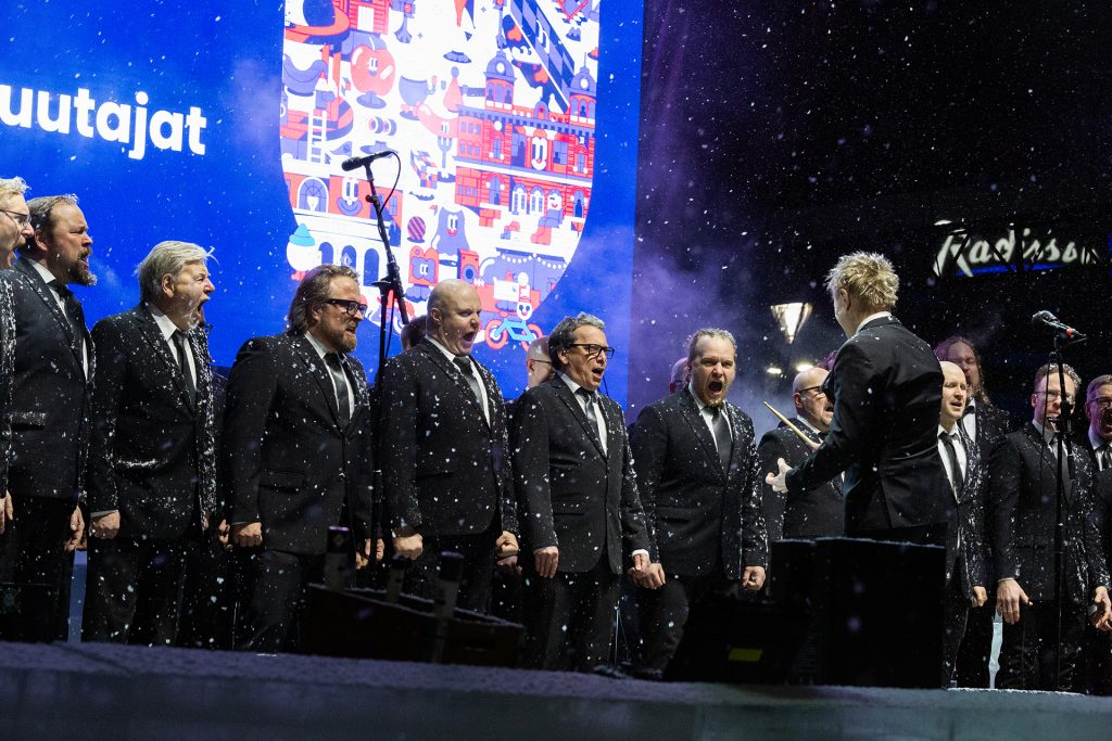 Mieskuoro lavalla lumisateessa.