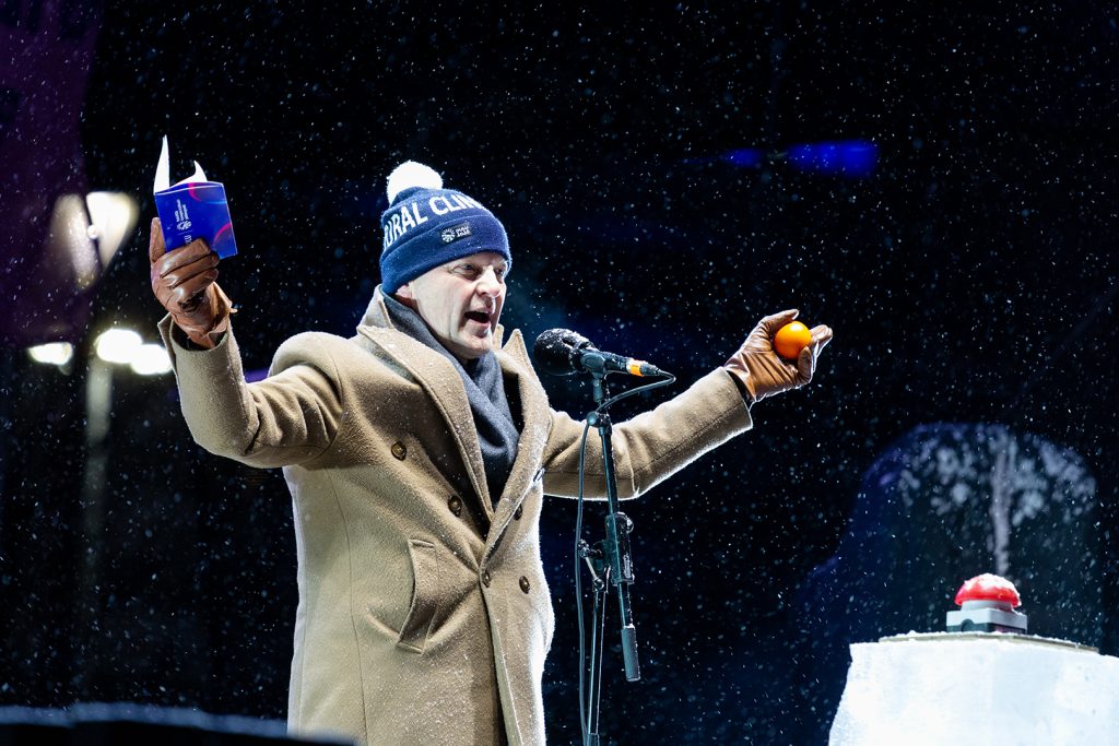 Pipopäinen kaupunginjohtaja tuulettaa lavalla.