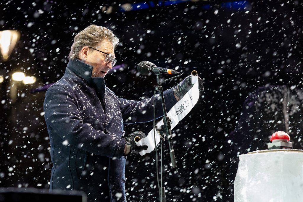 Mies lukee paperikääröstä lumisateessa.