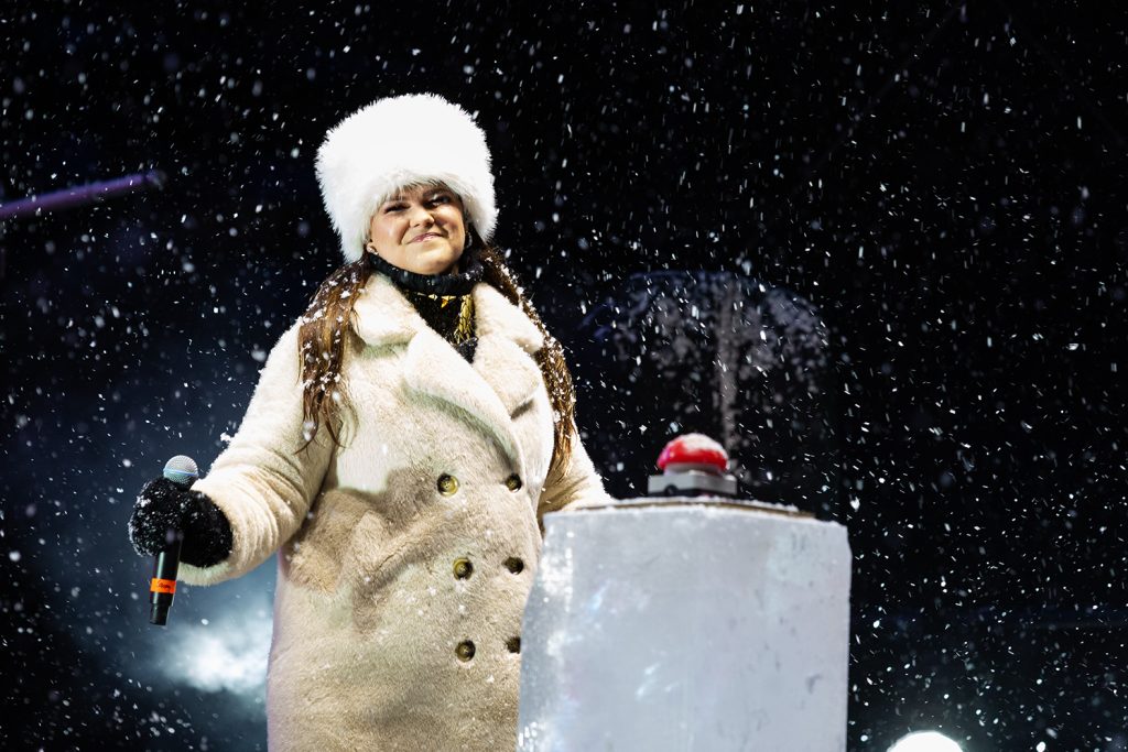 Laulaja valkoisessa karvahatussa ja takissa lavalla.