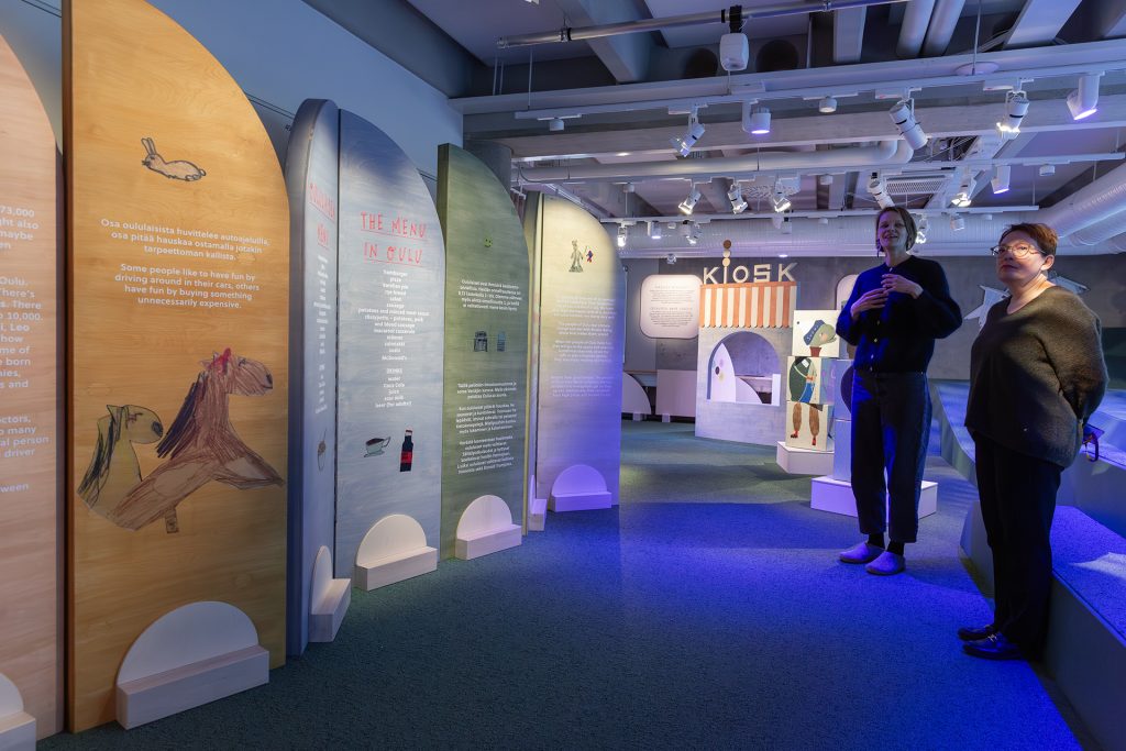 Kaksi naista hämärässä näyttelytilassa.