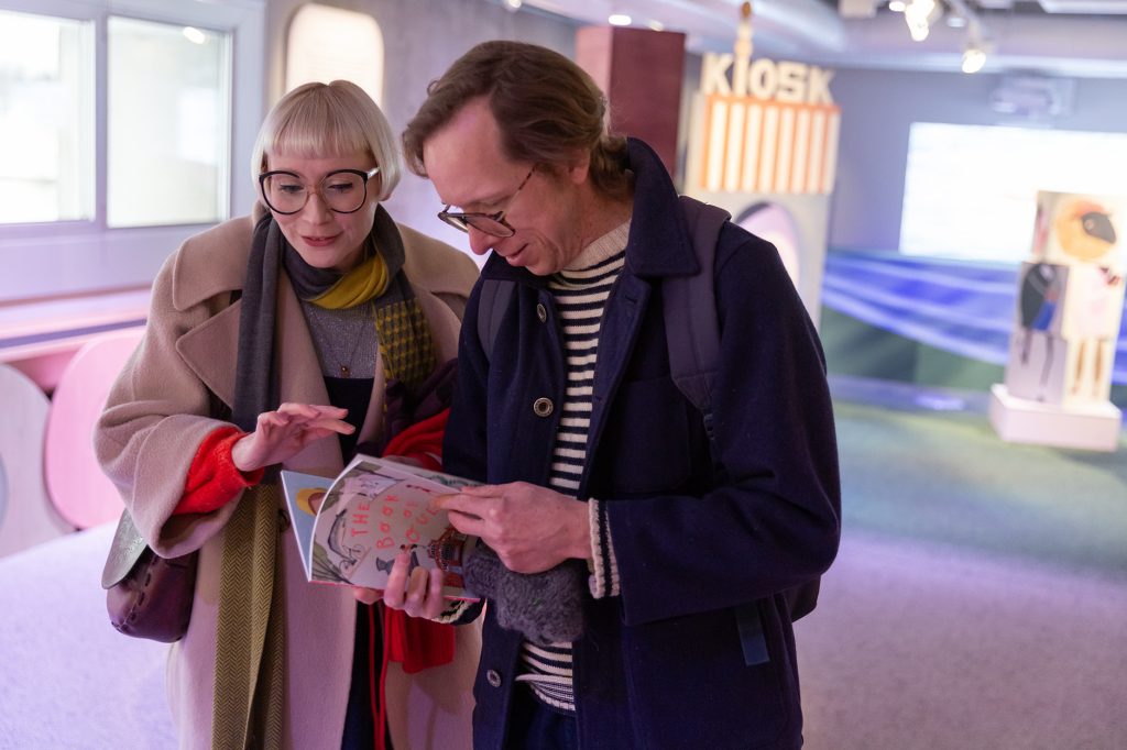 Mies ja nainen lukevat kirjaa näyttelytilassa.