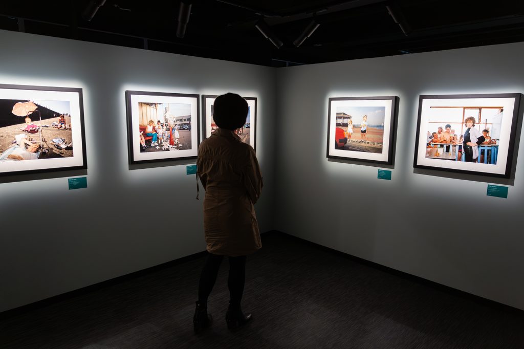 Nainen tutkii valokuvateoksia galleriassa.