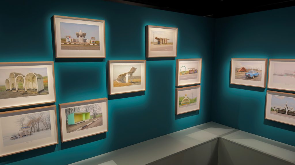 Valokuvateoksia vihreällä seinällä.