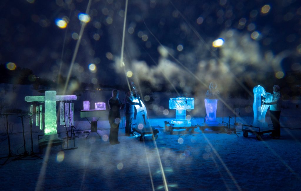 Ryhmä soittajia jäällä hämärässä valaistuksessa.