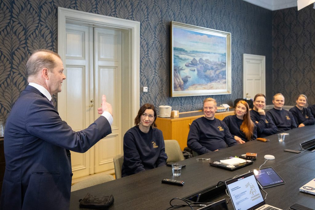 Kaupunginjohtaja puhuu pöydän ääressä istuville ihmisille.