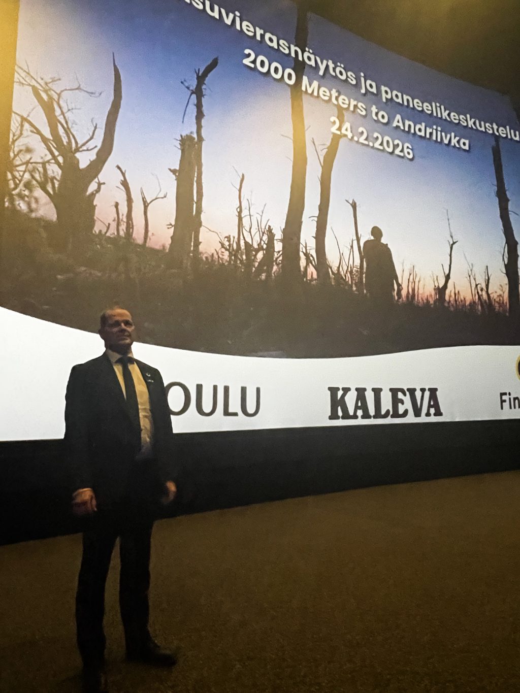 Kaupunginjohtaja seisoo valkokankaan edessä.