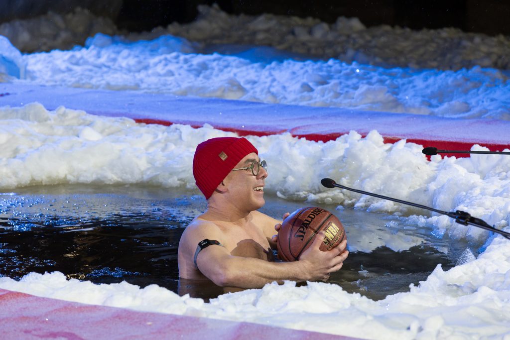 Pipopäinen mies koripallo käsissään avannossa.