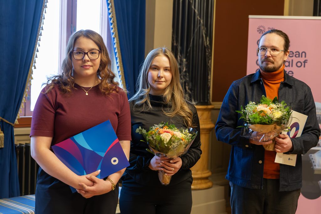 Kaksi naista ja mies kukitettuna.