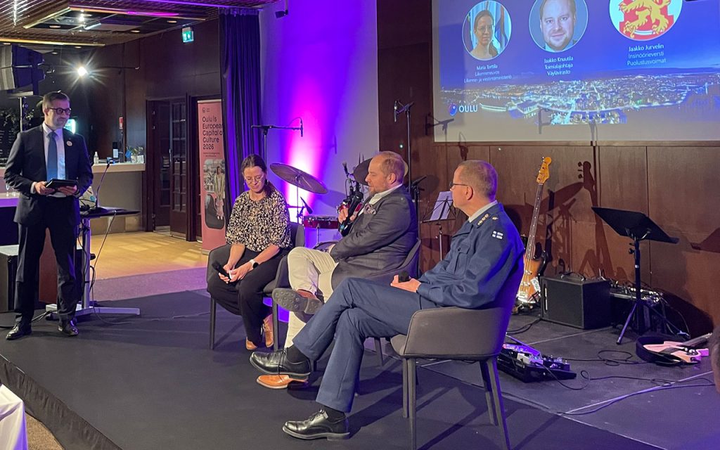 Ihmisiä lavalla paneelikeskustelussa.