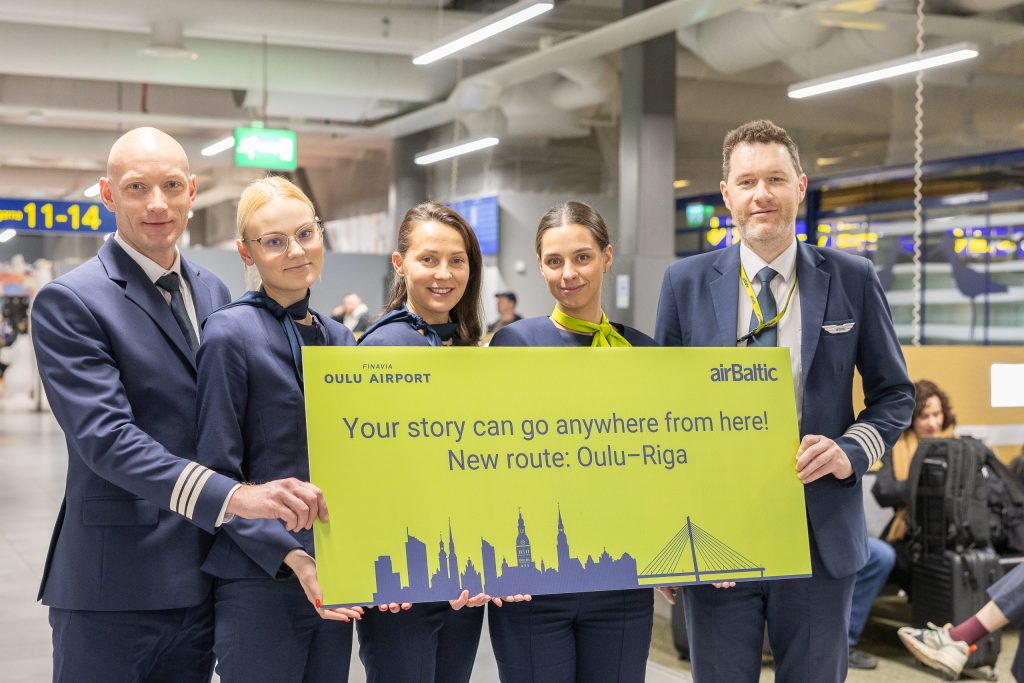 Lentohenkilökunta pitelee suurta keltaista tervetulokylttiä.