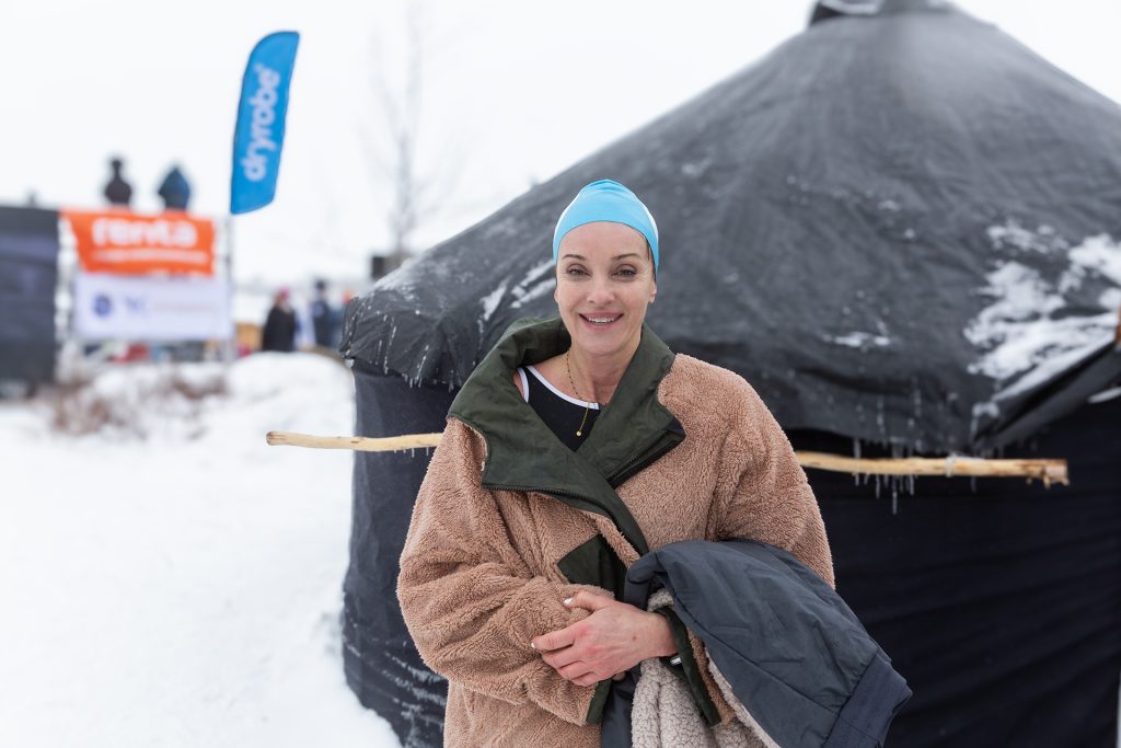 Nainen kylpytakissa ja uimalakissa telttasaunan edessä.