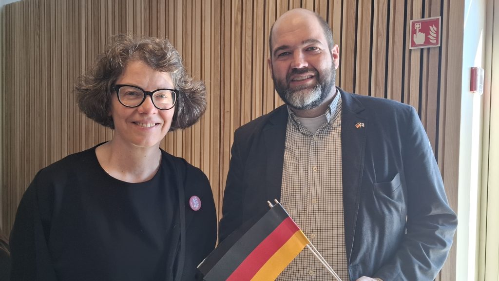 Nainen ja mies poseeravat, miehellä kädessään pieni Saksan lippu.