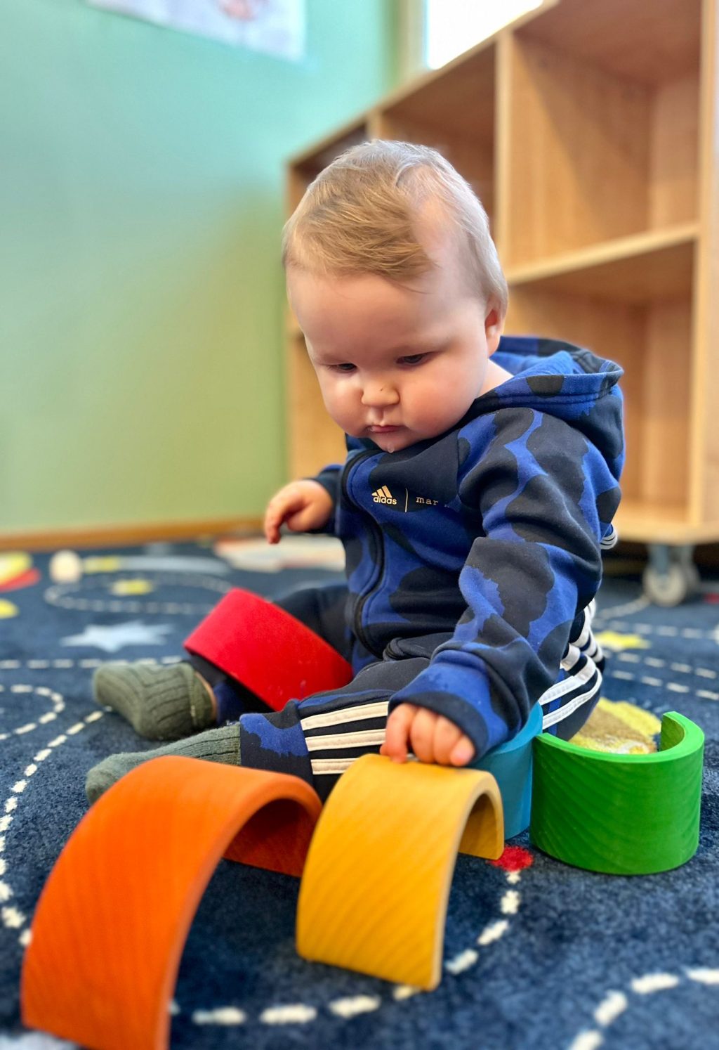 Vauva leikkii värikkäillä leluilla sinisellä matolla.