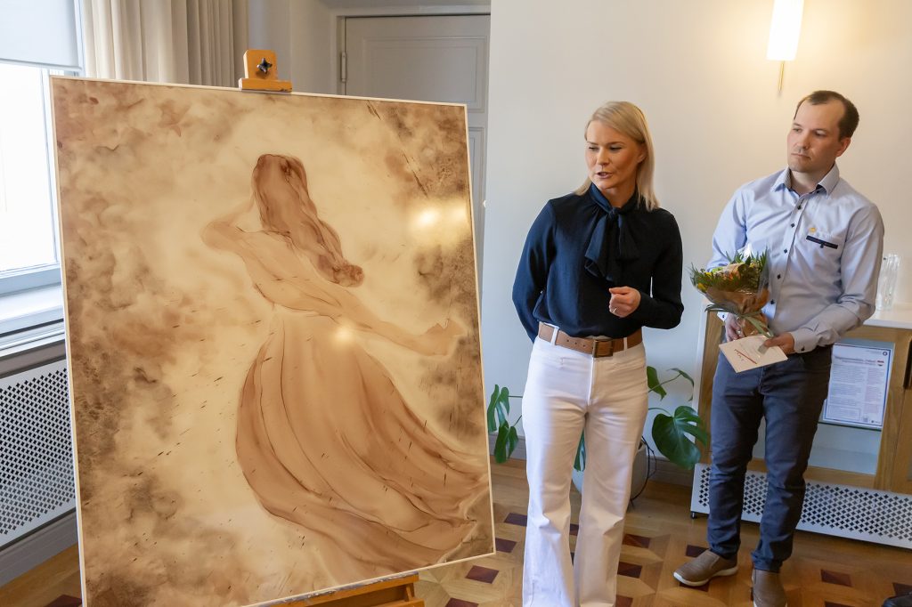 Mies ja nainen katselevat suurta taulua, jossa naishahmo.