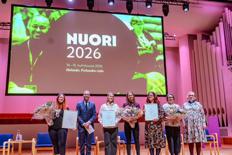 Ihmisiä lavalla palkintojenjaossa.