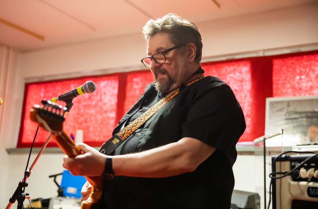 Silmälasipäinen mies soittaa sähkökitaraa