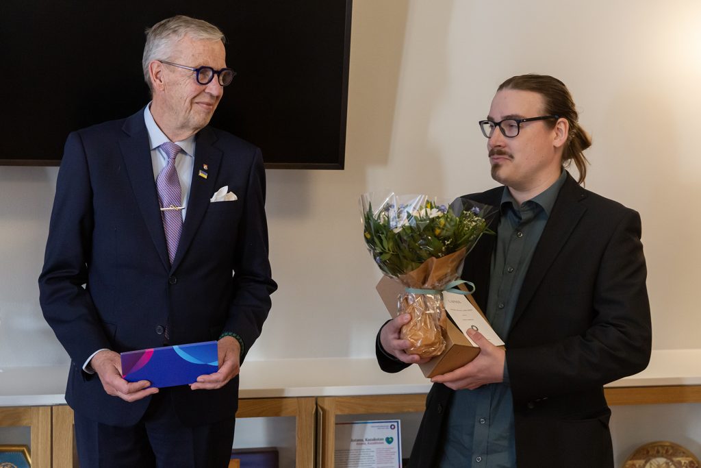 Kaksi miestä, toisella kukkapuska käsissään.