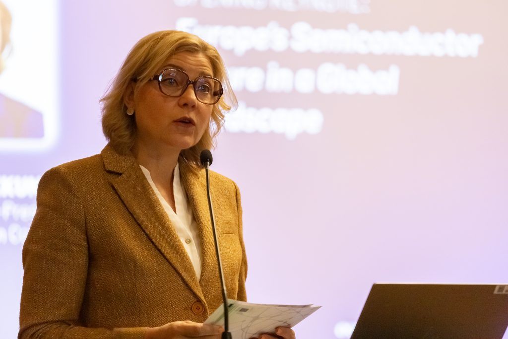 Vaalea, silmälasipäinen nainen puhuu.