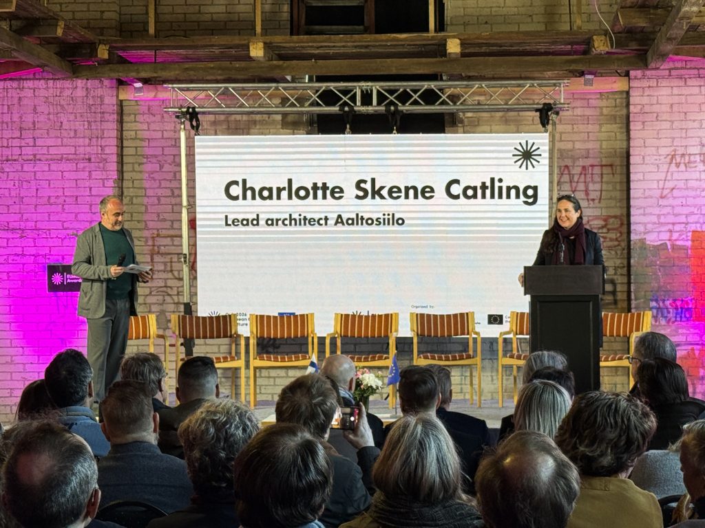 A man and a woman on stage in front of and audience in the silo.