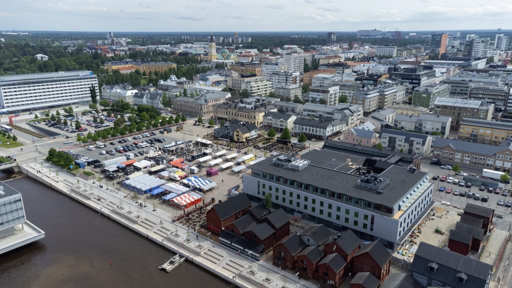 Ilmakuva kesäisestä kaupungista meren suunnasta kuvattuna, etualalla kauppatori ja punaisia aittoja.