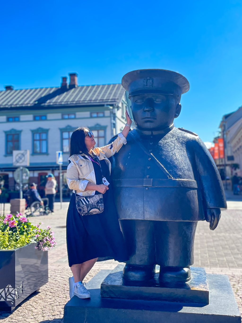 Tummahiuksinen nainen koskettaa Toripolliisi-patsaan kaulaa.