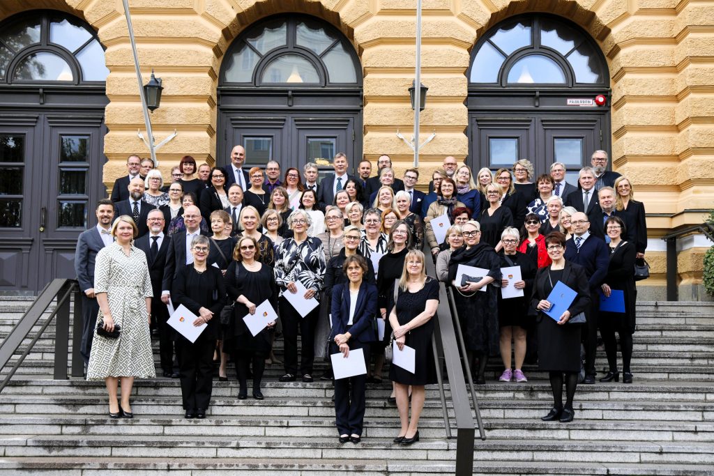 Ihmisiä ryhmäkuvassa kaupungintalon portailla.