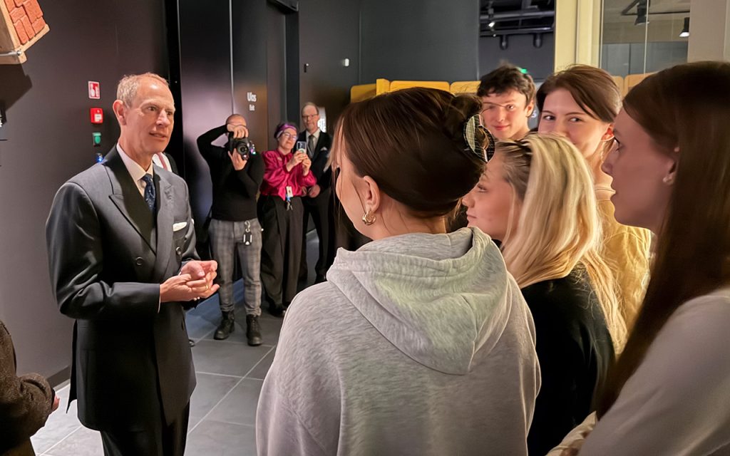 Mies juttelee nuorten kanssa museossa.